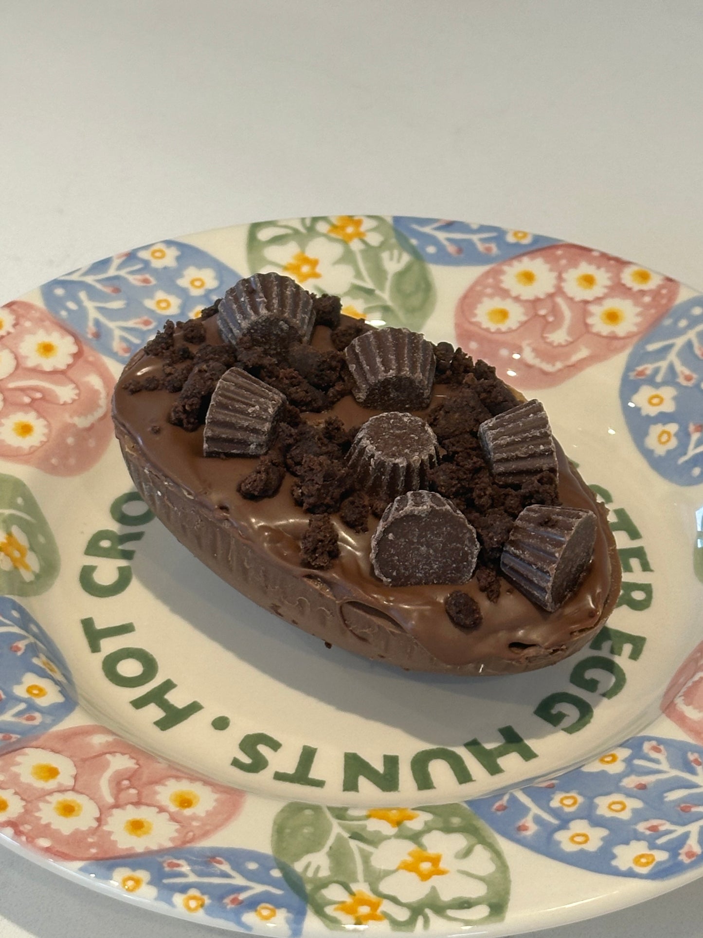 Half a chocolate Easter egg filled with Reece filling and decorated with mini Reece and crumbled brownie.