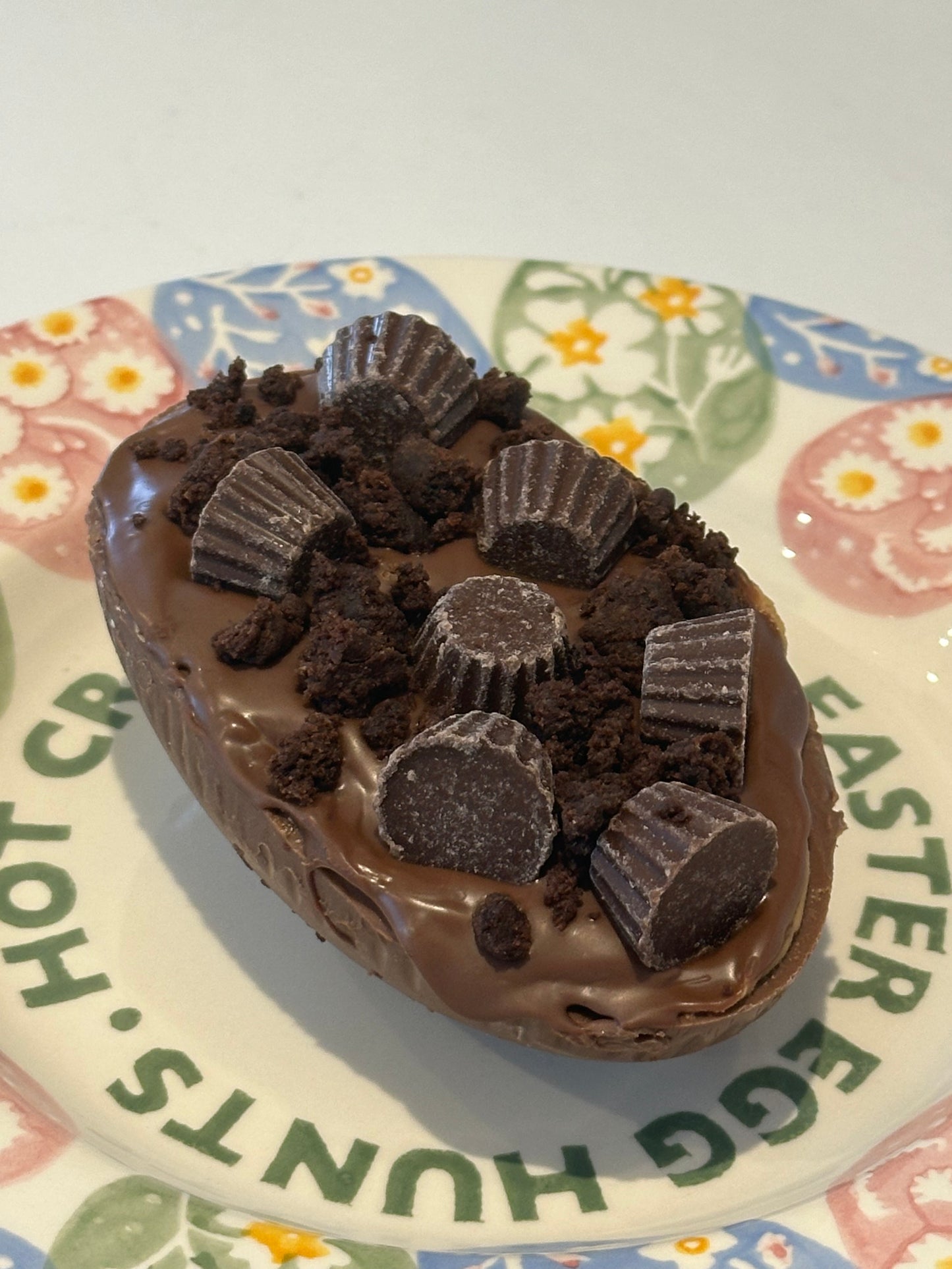 Half a chocolate Easter egg filled with Reece filling and decorated with mini Reece and crumbled brownie.
